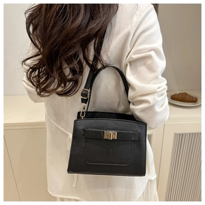 Black Saffiano leather bag with gold turn-lock closure on white cabinet background