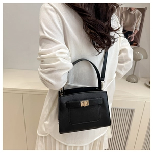 On-body view of a black structured tote bag with gold hardware and top handle for women