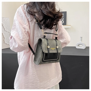 Detail of grey crossbody backpack with gold buckles worn by model in minimalist setting