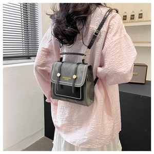 Close-up of contrast grey and black mini backpack with gold FASHION & BAGS logo and stitching