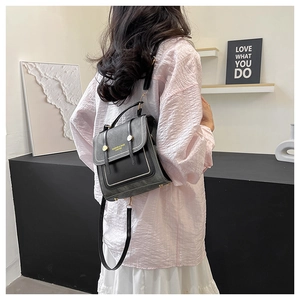 Detail view of dark grey PU leather convertible backpack with gold studs and handle