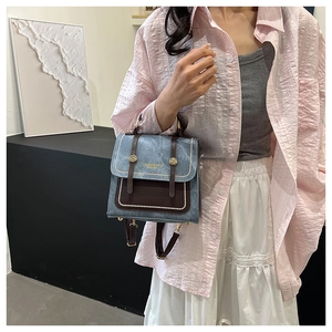 Detail of blue denim and brown leather mini crossbody bag with fashion lettering