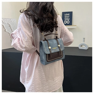 Detail of blue denim and brown leather mini backpack with gold rivets and straps