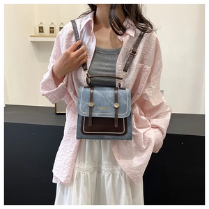 Detail of retro denim and brown leather backpack with gold buckles in home setting