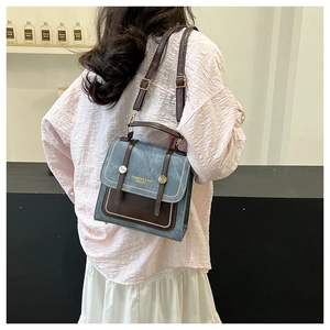 Detailed view of vintage denim crossbody bag with brown leather trim worn by model