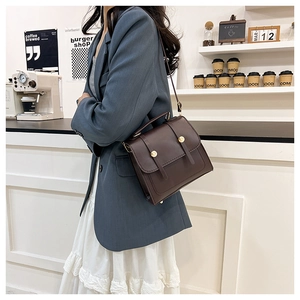 Detail of vintage dark brown multi-functional handbag with gold rivets in a cafe setting