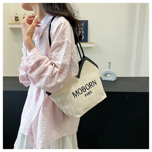 Detailed close-up of woven straw tote bag with black trim and MOBORN PARIS lettering