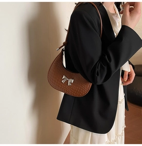 Detail of vintage brown crescent bag with woven texture and silver bow buckle