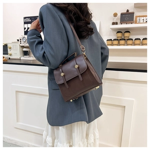 Detail of dark brown vintage faux leather crossbody bag styled with a professional outfit
