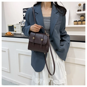 Detail of vintage brown leather crossbody bag featuring gold buckles in a cafe setting