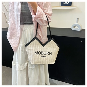 Detalle de bolso tote de paja beige con bordado negro y correas de cuero fino