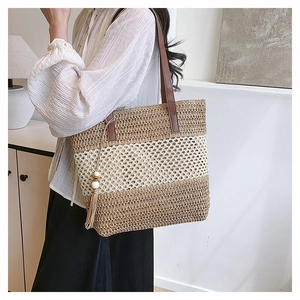 Detail of hand-woven straw tote with leather straps and decorative wooden bead tassels