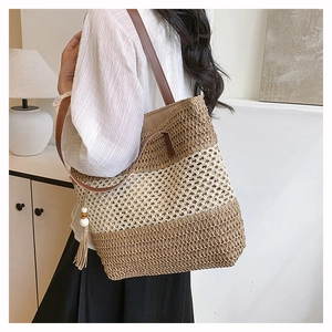 Detail of woven tote bag with beige and brown stripes and leather shoulder straps