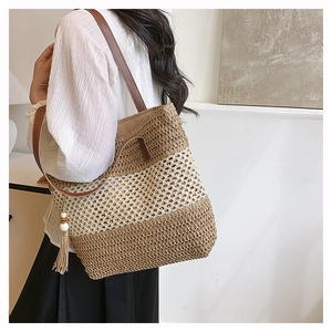 Detail of tricolor woven straw tote bag featuring leather straps and stylish side tassels