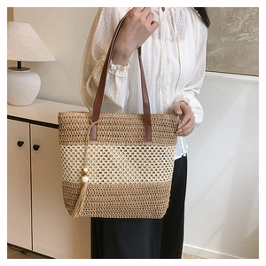 Fashionable woven straw tote bag with brown leather straps and beaded tassel detail