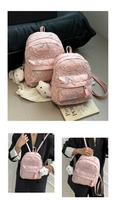 Detail of pink quilted backpack with bow embroidery and soft white cloud keychain