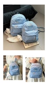Detail of light blue quilted backpack featuring colorful 3D butterfly embroidery and chain