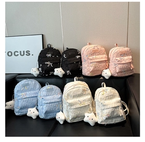 Close-up of quilted bow schoolbags in black, pink, blue and beige with star charms