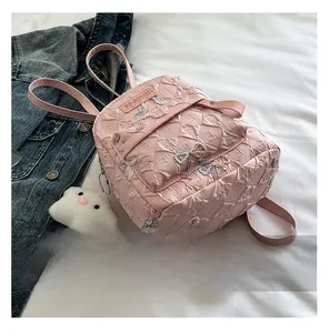 Detail of pink quilted backpack with colorful bow embroidery and cloud plush charm