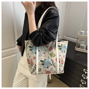 Floral print tote bag detail showing colorful pattern with white handles and leather jacket