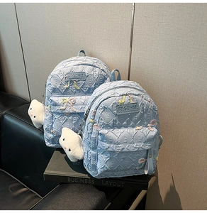 Close-up of light blue quilted mini backpack with sequined bow and cloud charm