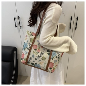Detail showing the thick floral tapestry fabric and brown leather handle of the tote bag