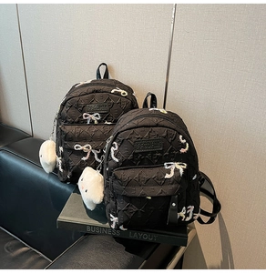 Detail of black quilted backpacks with colorful butterfly embroidery and plush charms