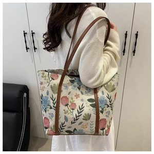 Detail view of large floral print tote bag with brown straps worn on the shoulder