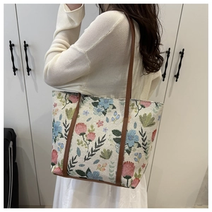 Sac fourre-tout en toile à motif floral avec bandoulières marron porté par un mannequin