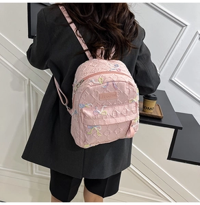 Detail of pink quilted backpack with colorful bow embroidery and brand logo label