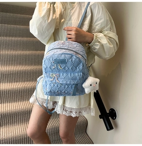 Detail of light blue quilted backpack with butterfly embroidery and plush sheep charm