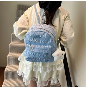 Close-up of light blue quilted backpack with embroidered bow and star plush charm