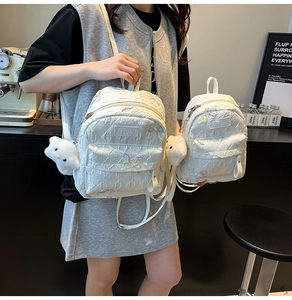 Detailed comparison of large and small quilted white backpacks with colorful embroidery