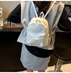 Detail of white quilted mini backpack with embroidery and silver dual zippers on leather