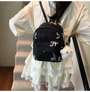 Detail of black quilted mini backpack with bow embroidery and star plush pendant