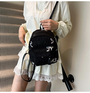 Detail of black quilted mini backpack with colorful sequined bows and brand logo