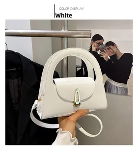 Detail der weißen Leder-Schultertasche mit rundem Griffausschnitt und Metallverschluss