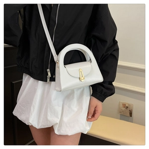 Detailed side view of white leather semi-circular bag with golden buckle on a model