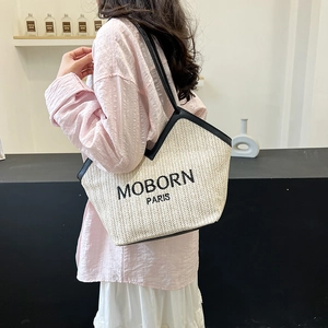 Minimalist straw tote bag with black leather straps and embroidered letters on the shoulder