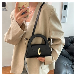 Mirror selfie showing the scale of a black semi-circle handbag with gold buckle