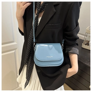 Detail of light blue crossbody bag with magnetic flap and white Fashion Trend logo text