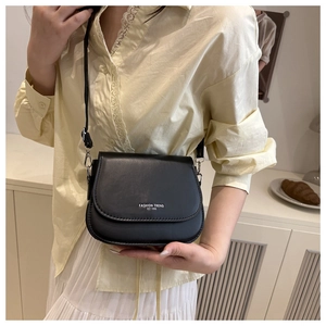 Close-up of black saddle bag on model showing FASHION TREND EST 1996 text and leather texture