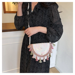 Détail des pompons tissés colorés et texture paille bohème sur un sac besace blanc