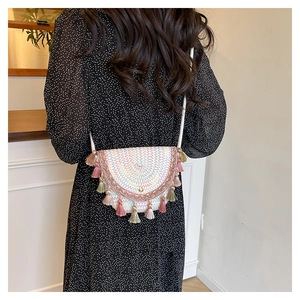Détail d'un sac bohème tissé avec broderie arc-en-ciel et des pompons colorés chic