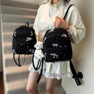 Black quilted backpack with bow embroidery and teddy charms shown on a model