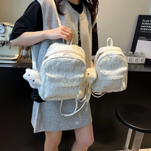 Quilted white backpack with wave embroidery and plush bear charm in two sizes