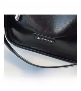 Details der schwarzen Ledertasche mit geprägtem Logo und feinen Silberbeschlägen