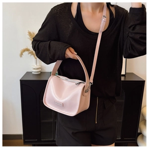 Makroaufnahme der rosa Handtasche aus Leder mit poliertem Silberlogo und Metallreißverschluss