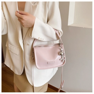 Detailansicht der rosa PU-Leder Umhängetasche mit silbernem Hundeanhänger und Logo