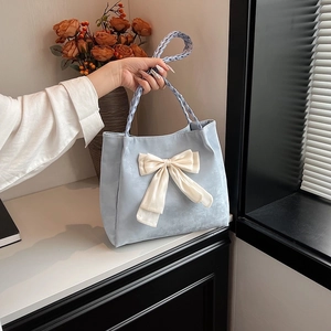 Elegant light blue tote bag with a cream ribbon bow and braided handles for women